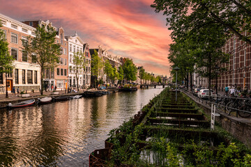 Canal in amsterdam during sunset - tenement houses reflecting in the water