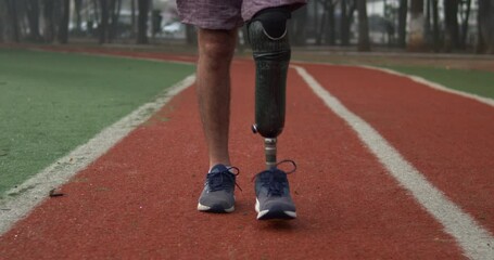 One disabled athlete walking forward with prosthetic leg outdoors - Powered by Adobe