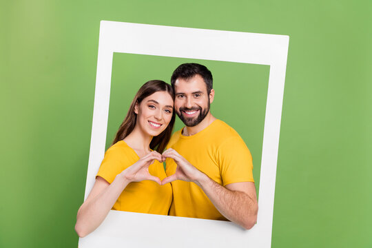 Photo of two lovely cheerful people hands showing heart symbol paper album card window isolated on green color background