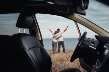 View From Car Interior, Young Couple on a Road Trip, Man and Woman Embracing on Sea Background