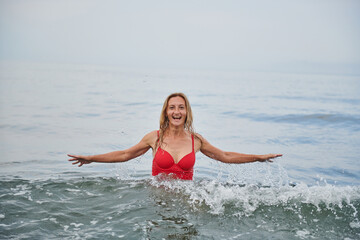 laughs a girl in the sea in a red swimsuit