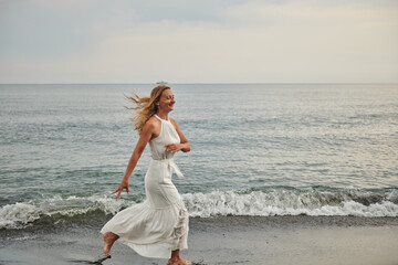 a girl in a white dress running on the beach