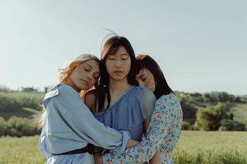 THREE HAPPY GIRLS EMBRACED IN THE COUNTRYSIDE. 