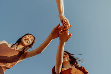 GIRLS HOLDING THEIR HANDS. VIEW FROM BELOW. 