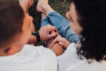 Close Up Back View of Man and Woman Holding by Hands Sitting on the Ground Outdoors, Middle Aged Couple in Love