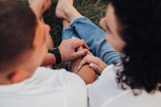 Close Up Back View Of Man And Woman Holding By Hands Sitting On The Ground Outdoors, Middle Aged Couple In Love