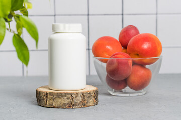 Mockup medical bottle of vitamins or pills with apricots at the background, multivitamin complex for good vision