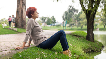 Naklejka na ściany i meble latin woman breathing air taking a moment from work in the park bogota colombia