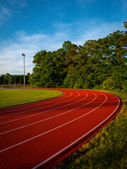 Tranquil landscape at the track and field with curved lines and trees under the blue cloudy sky at sunrise