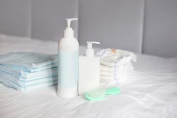 body cream, comb, disposable diaper and diapers on a bed. Baby care. First days of life. Feeding and motherhood