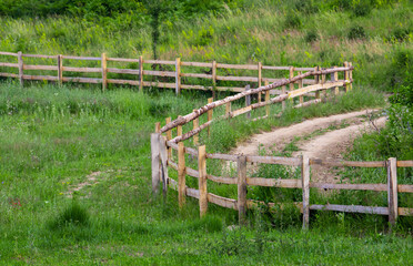 a dirt road and a wooden fence meandering on the hill slope