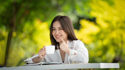 Young stylish woman drinking coffee and using a cup and to go in a park, young people female hand holding a cup of take away drinking coffee on natural morning