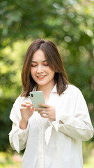 Thoughtful smile woman in park using smart phone, Portrait of a young charming business woman checking online Business work on her smart phone outdoors in the park on soft green back ground