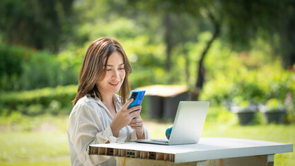 Thoughtful smile woman in park using smart phone, Portrait of a young charming business woman checking online Business work on her smart phone outdoors in the park on soft green back ground