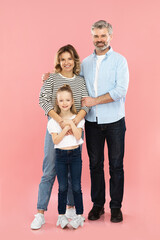 Cheerful Parents And Little Daughter Embracing Over Pink Background