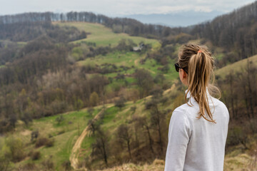 Beautiful mountains and standing young woman on top hills. Landscape with mountain peak, forest. Travel concept