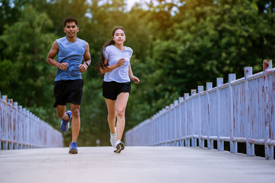 Young couple running together on road across the bridge. Couple, fit runners fitness runners during outdoor workout.