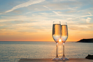 Pair of champagne flutes with prosecco in from of sunset in Woolacombe, North Devon, UK