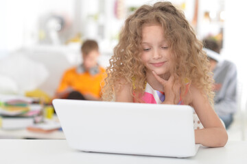 Cute schoolgirl using  laptop in the room