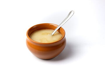 Pure cow ghee in ceramic bowl with steel spoon on white background