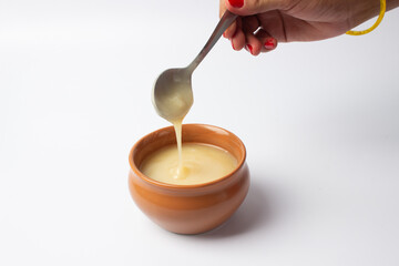 Pure cow ghee in ceramic bowl on white background with ghee spoon in hand
