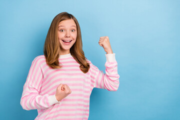 Portrait of delighted positive girl raise fists celebrate triumph success isolated on blue color background