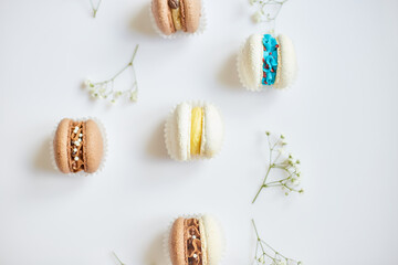 Top view set of different french cookies macaroons, cake macarons with flowers on white background, colorful almond cookies, pastel colors.