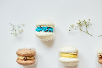Top view set of different french cookies macaroons, cake macarons with flowers on white background, colorful almond cookies, pastel colors.