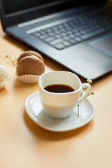 Flat lay, top view office table desk, workspace with laptop, macaroon with coffee cup and flowers, on orange background, working from home, distant work..