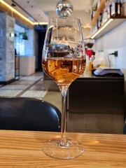 A glass of rose wine on a wooden table in a restaurant