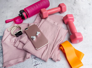 Fitness set with female clothing, dumbbells , bottle of water ,elastic band ,smartwatch and smartphone