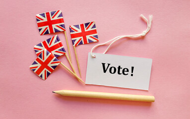 Vote word and UK paper flags on pink background  . The concept of voting, making choices. Elections...