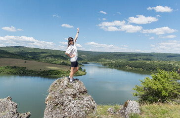 Fototapeta na wymiar Young beautiful traveler woman sitting on a rock above lake .Traveling in the summer nature