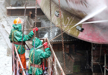 shipyard workers cleaning the hull of a ship