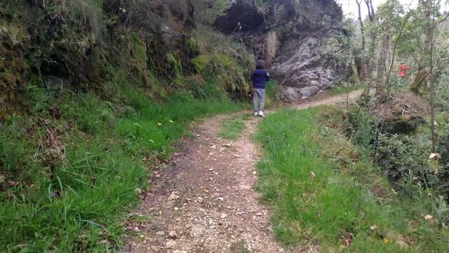 A girl with a boy shooting photographs in nature on the hiking trail next to the Sor River. Camera shot advancing. Lugo, Galicia, Spain
