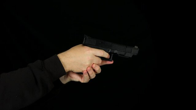 Side view of a man cocking and firing a hand gun pistol
