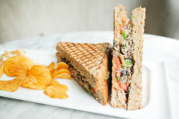 Tuna sandwich and chips on a plate on table ,