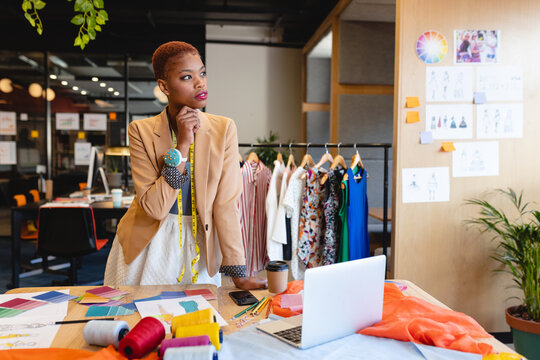 Thoughtful african american female fashion designer with hand on chin in studio office