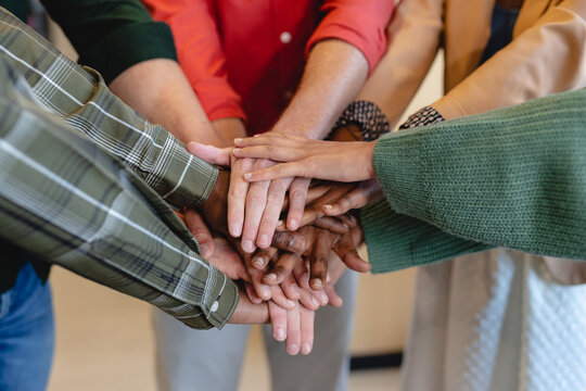 Midsection of multiracial fashion designers stacking hands in creative office