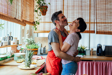 Cheerful couple hugging in kitchen
