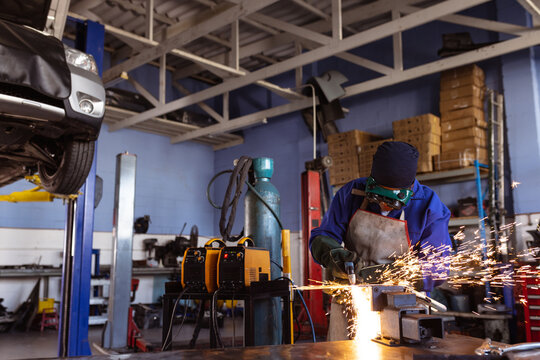 Mid adult african american female welder wielding car's part while working in workshop