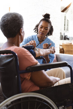 African american doctor examining senior woman's blood pressure with gauge and stethoscope at home