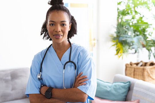 Portrait of confident african american female doctor with arms crossed standing against white wall
