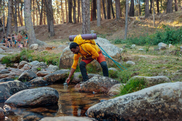 Young hiker taking water from mountain stream