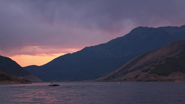 Boat floating in lake during colorful sunset in Utah on Deer Creek Reservoir.