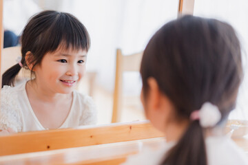 鏡で自分の顔を見る女の子