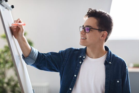 Smiling Young Male Entrepreneur Writing Notes On White Board In Office