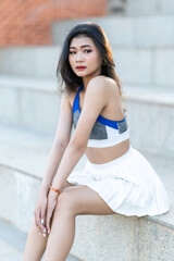 Naklejka premium Portrait of beautiful athletic young asian woman in fashionable sportswear standing and having rest after strong exercise training in garden the park,Outdoor Sporty concept