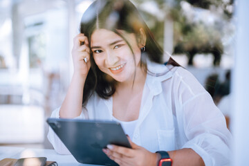 asian freelance people business female wearing smartwatch talking making using casual working with tablet for browsing internet, chatting and blogging and smartphone,notebook in coffee shop.