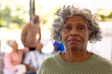 Close-up portrait of serious african american senior woman with multiracial friends in background - Powered by Adobe